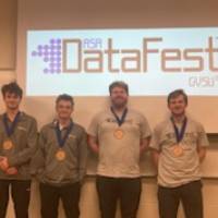 Four students awarded the Best Insight Award pose in front of the DataFest logo.